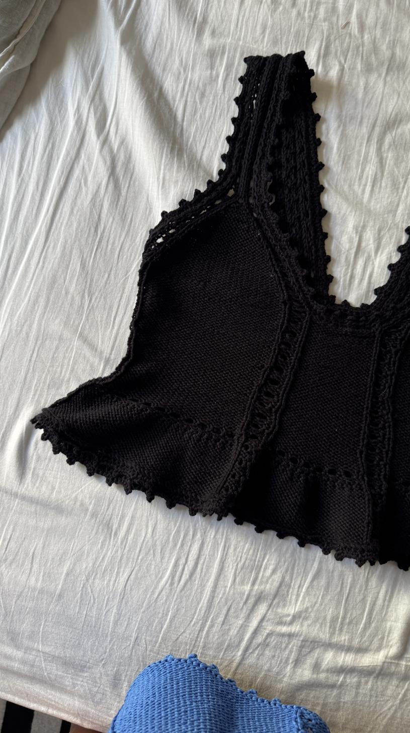 Black hand-knitted top with a scalloped lace edge, laid flat