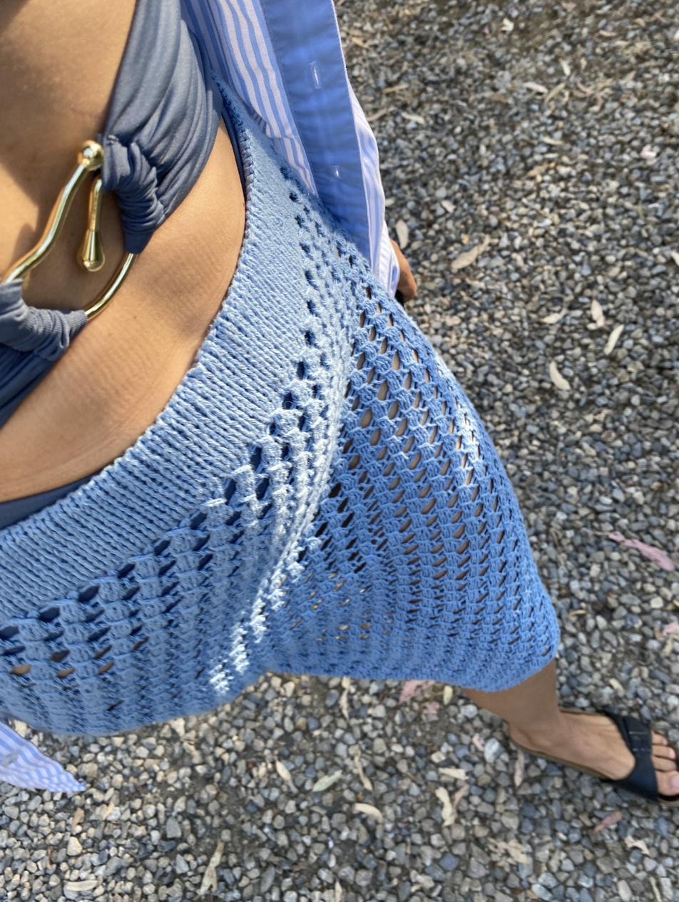 Detail of a light blue crocheted skirt with an openwork lace border, worn outdoors